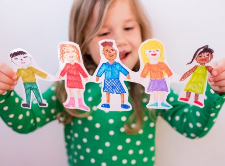 girl holding paper homemade garland of people of different races. Happy international children day