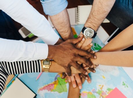 Group of friends stacking hands above world map