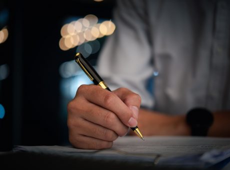 Hand holding pen checklist paper work on desk. Signing information contract and